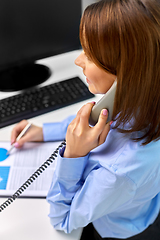 Image showing businesswoman calling on desk phone at office