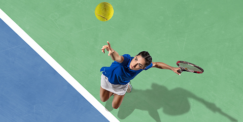 Image showing Young woman in blue shirt playing tennis. Youth, flexibility, power and energy.