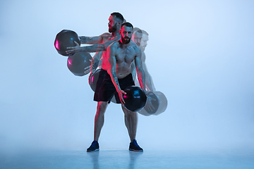 Image showing Young caucasian bodybuilder training over blue background