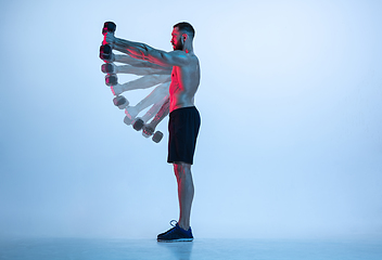 Image showing Young caucasian bodybuilder training over blue background