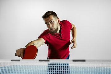 Image showing Young man playing table tennis on white studio background