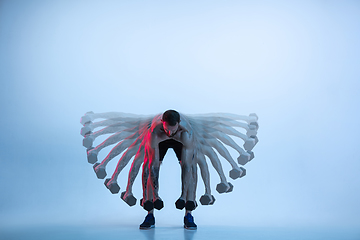 Image showing Young caucasian bodybuilder training over blue background