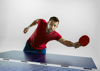 Image showing Young man playing table tennis on white studio background