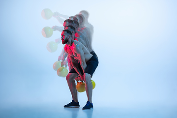 Image showing Young caucasian bodybuilder training over blue background