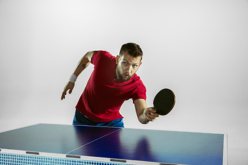 Image showing Young man playing table tennis on white studio background