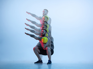 Image showing Young caucasian bodybuilder training over blue background