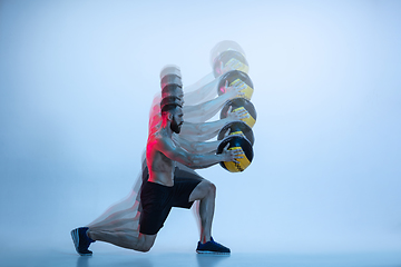 Image showing Young caucasian bodybuilder training over blue background