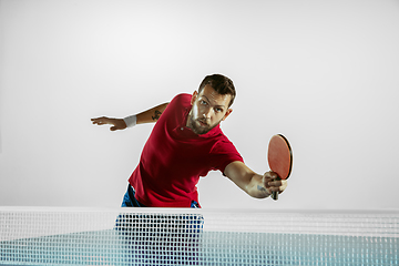 Image showing Young man playing table tennis on white studio background