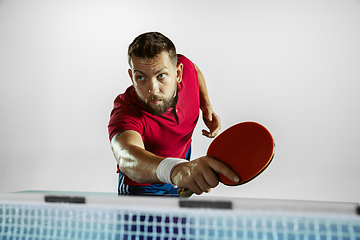 Image showing Young man playing table tennis on white studio background