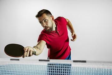 Image showing Young man playing table tennis on white studio background