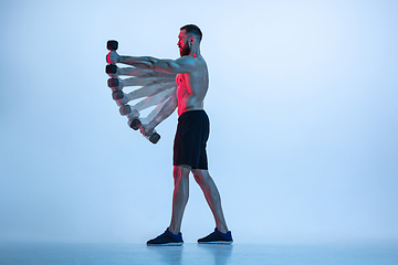 Image showing Young caucasian bodybuilder training over blue background