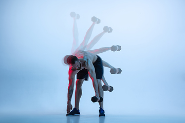 Image showing Young caucasian bodybuilder training over blue background