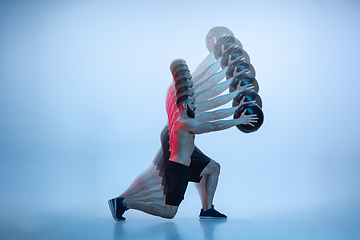 Image showing Young caucasian bodybuilder training over blue background