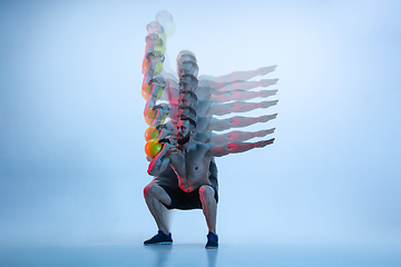 Image showing Young caucasian bodybuilder training over blue background