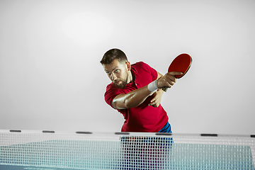 Image showing Young man playing table tennis on white studio background