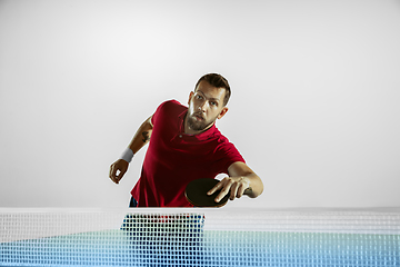 Image showing Young man playing table tennis on white studio background