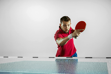 Image showing Young man playing table tennis on white studio background