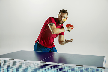 Image showing Young man playing table tennis on white studio background