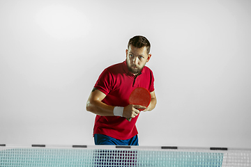 Image showing Young man playing table tennis on white studio background