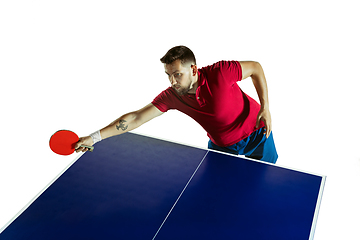 Image showing Young man playing table tennis on white studio background