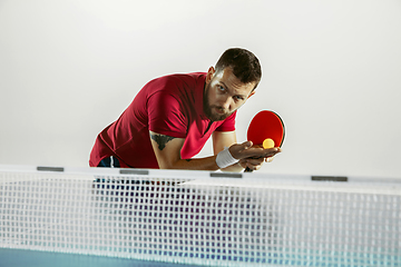 Image showing Young man playing table tennis on white studio background