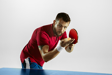 Image showing Young man playing table tennis on white studio background