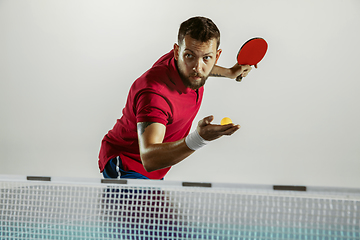 Image showing Young man playing table tennis on white studio background