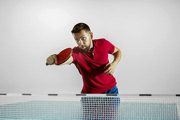 Image showing Young man playing table tennis on white studio background