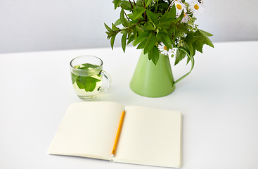 Image showing herbal tea, notebook and flowers in jug on table