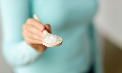 Image showing close up of woman with sea salt on wooden spoon