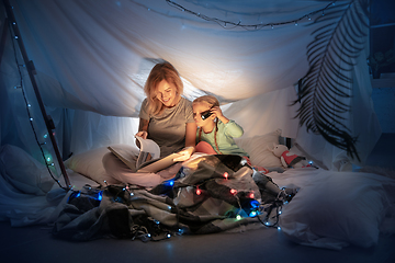 Image showing Mother and daughter sitting in a teepee, reading stories with the flashlight