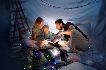 Image showing Family sitting in a teepee, reading stories with the flashlight