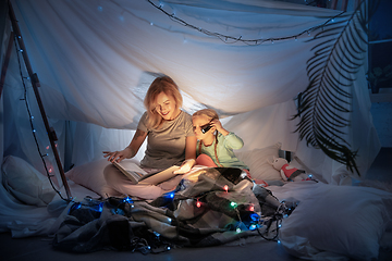 Image showing Mother and daughter sitting in a teepee, reading stories with the flashlight