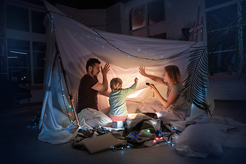 Image showing Family sitting in a teepee, reading stories with the flashlight