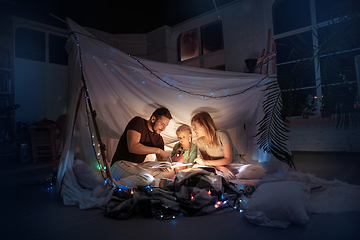 Image showing Family sitting in a teepee, reading stories with the flashlight