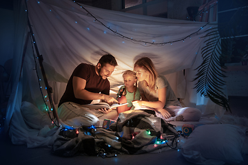 Image showing Family sitting in a teepee, reading stories with the flashlight