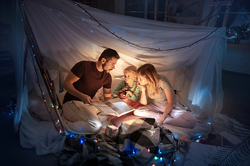 Image showing Family sitting in a teepee, reading stories with the flashlight