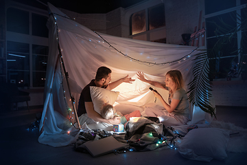 Image showing Family sitting in a teepee, having fun with the flashlight