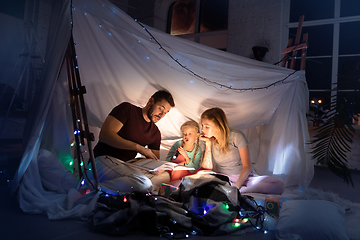 Image showing Family sitting in a teepee, reading stories with the flashlight