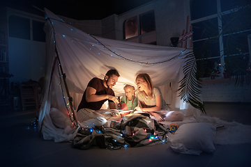 Image showing Family sitting in a teepee, reading stories with the flashlight