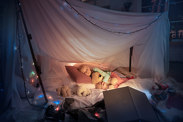 Image showing Little girl lying in a teepee, sleeping with the flashlight