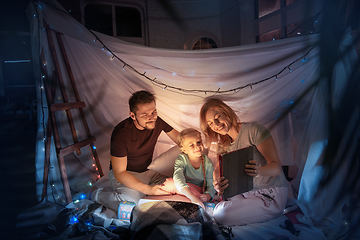 Image showing Family sitting in a teepee, having fun with the flashlight