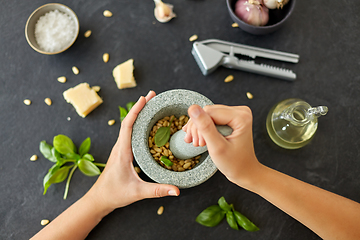 Image showing hands grinding pine nuts in mortar and pestle