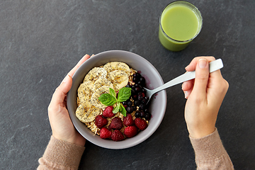 Image showing hands of woman eating cereal breakfast with spoon