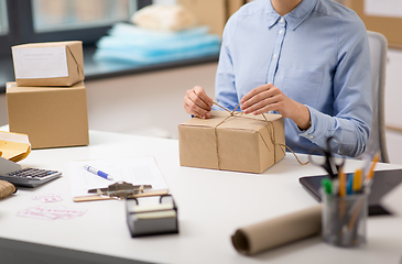 Image showing woman packing parcel and tying rope at post office