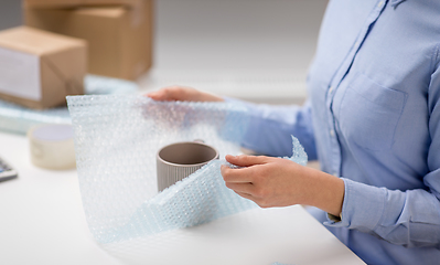 Image showing woman packing mug to parcel box at post office