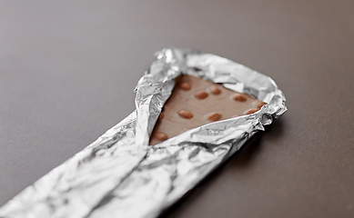 Image showing close up of milk chocolate bar with nuts in foil