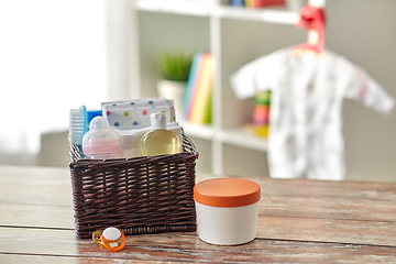 Image showing baby things in basket on wooden table at home