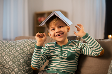 Image showing happy little boy with book having fun at home