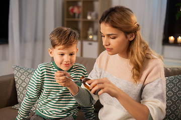 Image showing mother giving medication or cough syrup to ill son